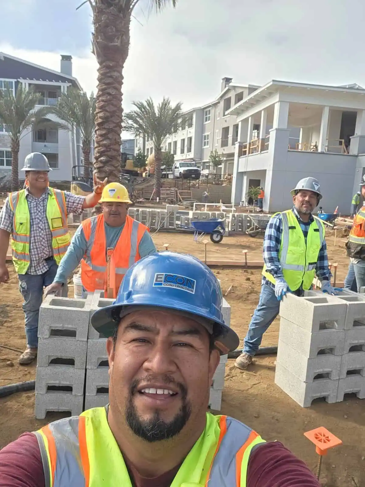 Construction workers at a building site with modern residential buildings in the background.